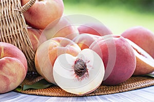 Fresh peach with slices on blurred greenery background, Peach fruit in Bamboo basket on wooden table in garden.