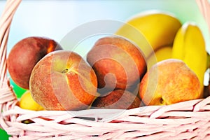 Fresh peaches and bananas. Wicker basket with summer fruits. Healthy food background.