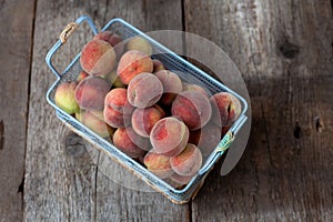 Fresh peaches fruits in basket on dark wooden rustic background, top view. Summer harvest of fruit. Still life. A group