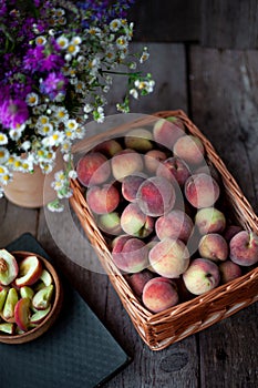 Fresh peaches fruits with in basket on dark wooden rustic background, top view. Summer harvest of fruits. Still life. A group of