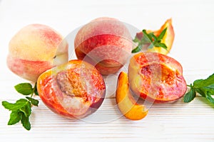 Fresh peaches with mint on wooden white background.