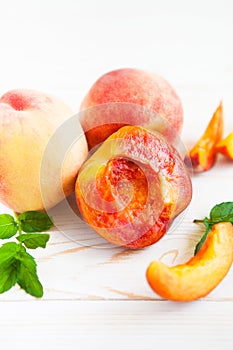 Fresh peaches with mint on wooden white background.