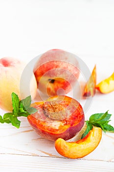 Fresh peaches with mint on wooden white background.