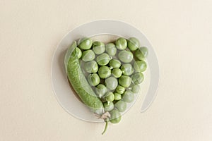 Fresh peas isolated on yelow background.Top view, selected focus. Heart shape