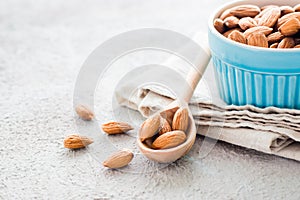 Fresh peeled almonds in a wooden spoon and in a bowl nearby on a light background. A source of vitamins and oils. Organic food.