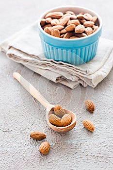 Fresh peeled almonds in a wooden spoon and in a bowl nearby on a light background. A source of vitamins and oils. Organic food.