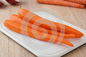 Fresh peeled long carrots on white chopping board