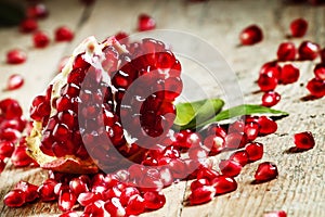 Fresh peeled pomegranates with ruby red beans on old wooden table, selective focus photo