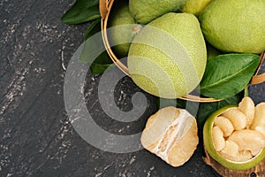 Fresh peeled pomelo, pummelo, grapefruit, shaddock on dark background in bamboo basket. Autumn seasonal fruit, top view, flat lay