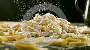 Fresh Penne Rigate pasta with flour on kitchen table