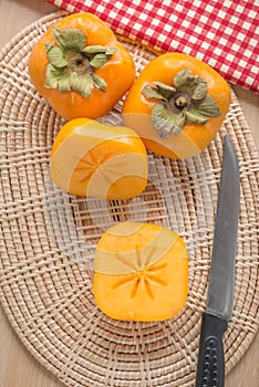 Fresh Persimmon fruit on wickerwork. Top view.