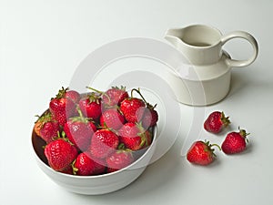 Fresh picked delicious strawberries in a white bowl with creamer