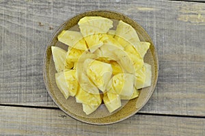 Fresh pieapple cut slices in brown plate on wooden background