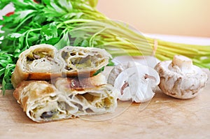 .Fresh piece of savory strudel stuffed with  leek and mushrooms served on a wooden plate,with mushrooms and parsley