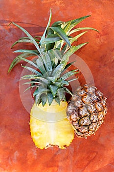 Fresh pineapple cut in half on orange rustic table