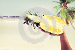 Fresh pineapple with in woman hands on tropical beach - vacation in summer