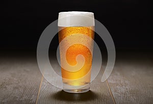 A fresh pint of India Pale ale IPA craft beer served in a cold pint glass at a brewery, black background