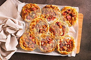 Fresh pizza pot pies with tomatoes, cheese and sausages on a wooden board top view