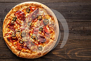 Fresh pizza with tomato sauce, black olives, mozzarella cheese, ham on wooden table closeup. Space for text or copy space. Pizza