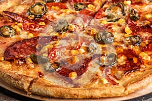 Fresh pizza with tomato sauce, black olives, mozzarella cheese, ham on wooden table closeup. Space for text or copy space. Pizza