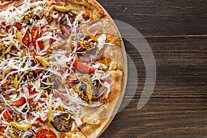 Fresh pizza with tomato sauce, black olives, mozzarella cheese, ham on wooden table closeup. Space for text or copy space. Pizza