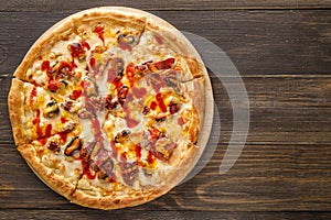 Fresh pizza with tomato sauce, black olives, mozzarella cheese, ham on wooden table closeup. Space for text or copy space. Pizza