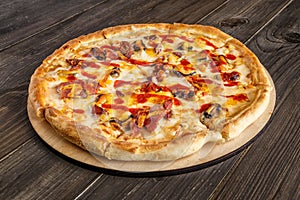 Fresh pizza with tomato sauce, black olives, mozzarella cheese, ham on wooden table closeup. Space for text or copy space. Pizza