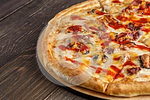 Fresh pizza with tomato sauce, black olives, mozzarella cheese, ham on wooden table closeup. Space for text or copy space. Pizza