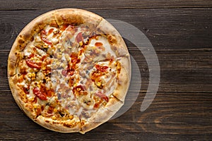 Fresh pizza with tomato sauce, black olives, mozzarella cheese, ham on wooden table closeup. Space for text or copy space. Pizza