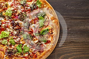 Fresh pizza with tomato sauce, black olives, mozzarella cheese, ham on wooden table closeup. Space for text or copy space. Pizza