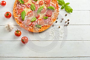 Fresh pizza with tomatoes, cheese and salami on a wooden table close-up