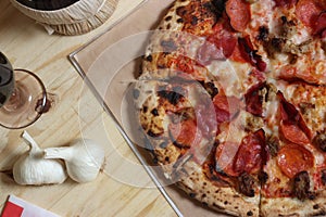 Fresh Pizza on Wooden Table at Restaurant With Bottle of Chianti Wine in Background