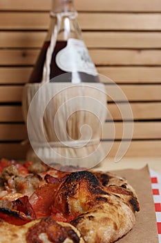 Fresh Pizza on Wooden Table at Restaurant With Bottle of Chianti Wine in Background