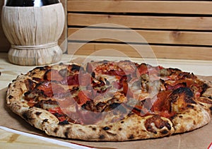 Fresh Pizza on Wooden Table at Restaurant With Bottle of Chianti Wine in Background
