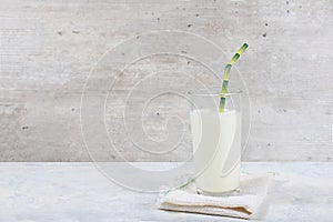 Fresh plain homemade yogurt,kefir,airan,lassi,smoothie in glass with paper bamboo tube on old gray background with space for text. photo