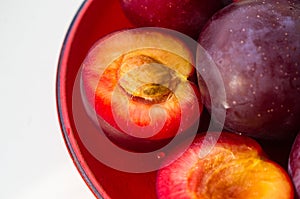fresh plum fruit in the red saucer on white background