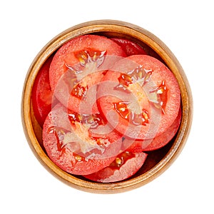 Fresh plum tomato slices, in a wooden bowl, isolated from above