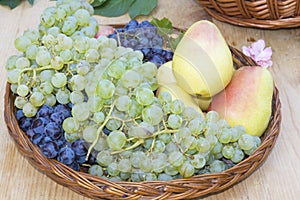 Fresh plums, grapes and pears in wooden basket