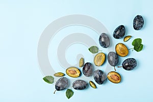 Fresh plums and leaves on background, top view