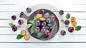 Fresh plums with leaves. Fruits. On a white wooden background.