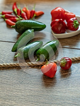 Fresh pod of spicy green jalapeno and chili pepper top view on wooden background