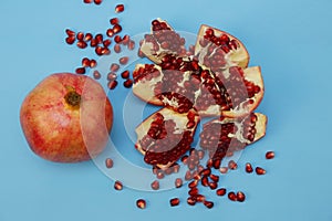 Fresh pomegranate and sliced â€‹â€‹pomegranate with red seeds on a blue background. Healthy fruits, vegan food, diet. Flat lay.