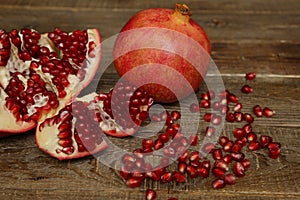 Fresh pomegranate and sliced â€‹â€‹pomegranate with red seeds on a wooden table. Healthy fruits, vegan food, diet.