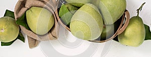 Fresh pomelo, pummelo, grapefruit, shaddock on white cement background in bamboo basket. Autumn seasonal fruit, top view, flat lay