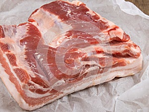 Fresh pork belly on white wrapping paper closeup