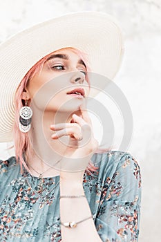 Fresh portrait charming feminine young woman with pink hair with sexy lips with vintage earrings in fashionable white hat in blue