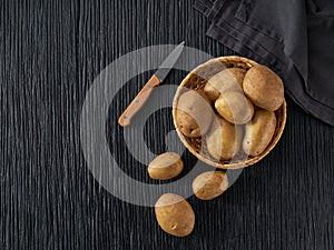 Fresh potato tubers on a black wooden table, top view