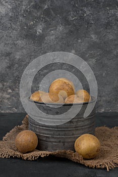 Fresh potatoes in a basket on a dark grey textured background, empty copy space for text