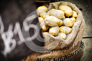 Fresh potatoes in burlap sack selling in market