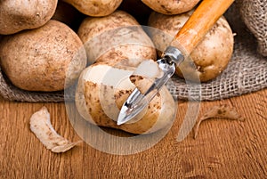 Fresh potatoes is peeled with a kitchen knife